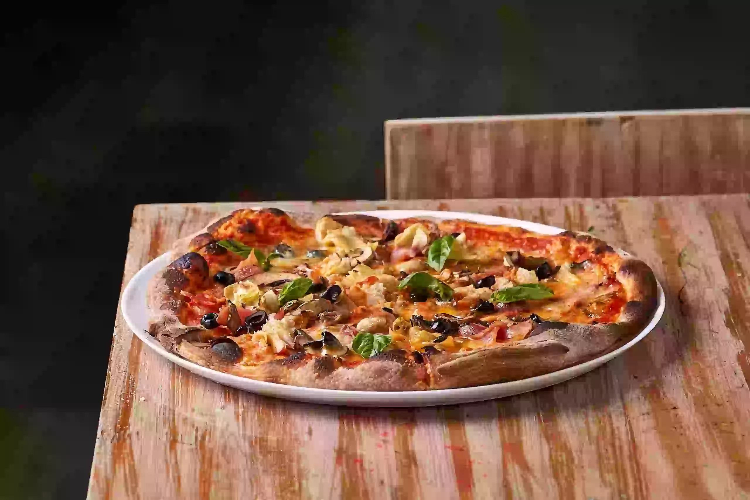 Pizza capricciosa con alcachofas y aceitunas negras